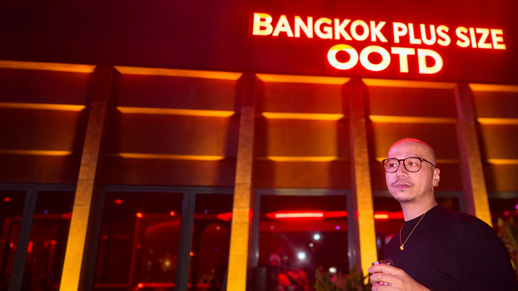 Polo Sumay in a warm red and amber Bangkok scene, with Bangkok Plus Size OOTD signage